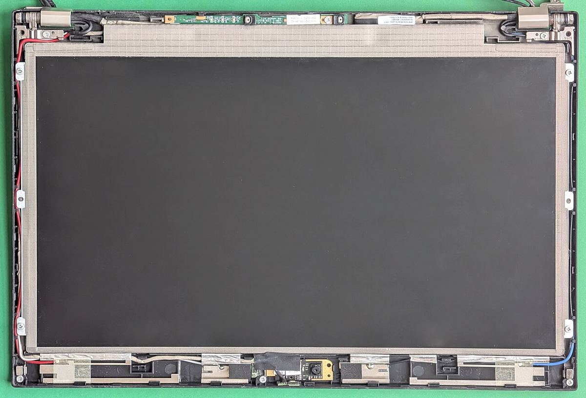A laptop display assembly taken apart, here from a ThinkPad X220. On a MacBook the panel is glued into the aluminium lid, not screwed into a frame, which is what makes the job harder.